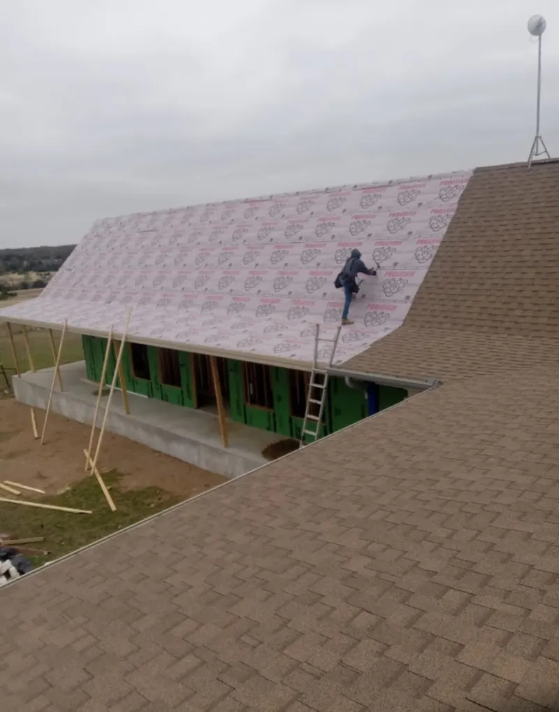 Worker preparing underlayment for a metal roof installation in Sand Lake